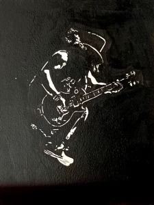 Cuadro pintado a mano de Slash tocando guitarra eléctrica con sombrero y melena en estilo stencil blanco sobre fondo negro