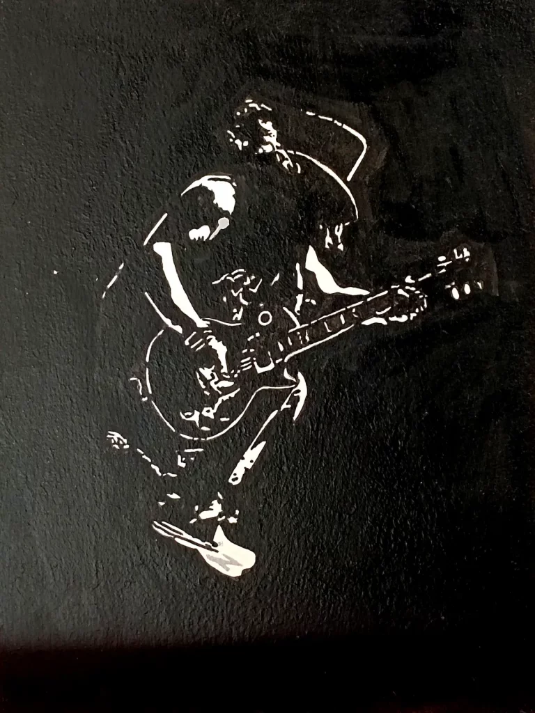 Cuadro pintado a mano de Slash tocando guitarra eléctrica con sombrero y melena en estilo stencil blanco sobre fondo negro