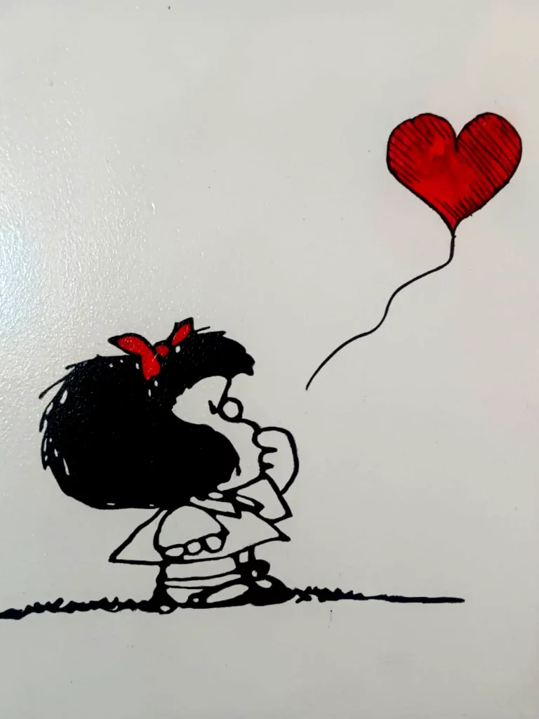 Cuadro de Mafalda observando un globo rojo con forma de corazón sobre fondo blanco.