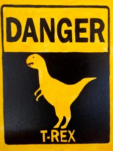 Cartel de peligro con silueta de Tyrannosaurus Rex en amarillo y negro inspirado en señales de advertencia.