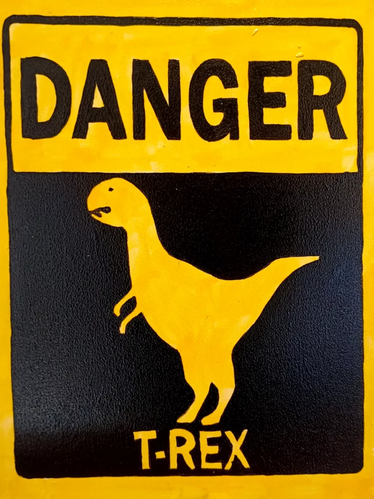 Cartel de peligro con silueta de Tyrannosaurus Rex en amarillo y negro inspirado en señales de advertencia.