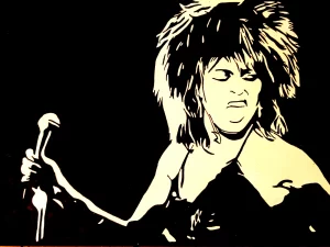 Retrato de Tina Turner en blanco y negro durante una actuación en directo con micrófono en la mano.